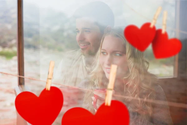 Couple with cups looking through window