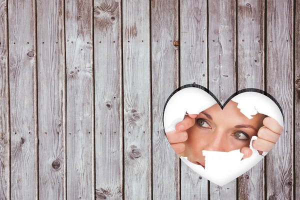 Woman looking through torn paper