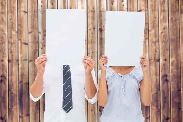 Couple holding paper over their faces