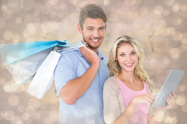 Couple holding shopping bags using tablet pc