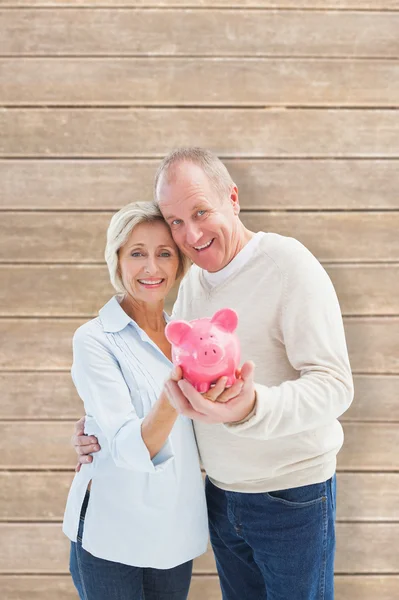 Mature couple showing piggy bank