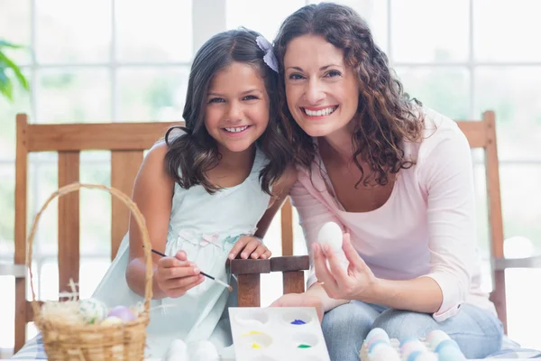 Happy mother and daughter painting easter eggs