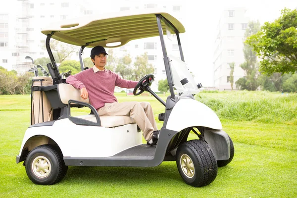 Golfer driving his golf buggy looking at camera