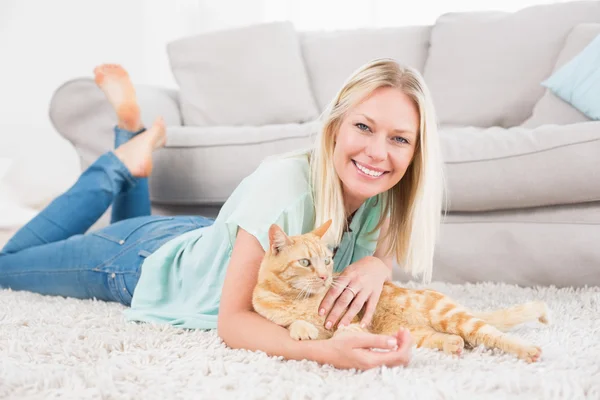 Happy woman with cat lying on rug