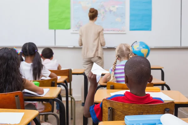 Naughty pupil about to throw paper airplane in class