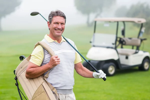 Happy golfer with golf buggy behind