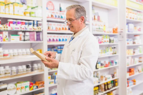 Smiling senior pharmacist reading prescription