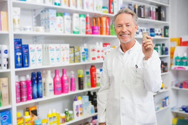 Senior pharmacist holding medicine jar