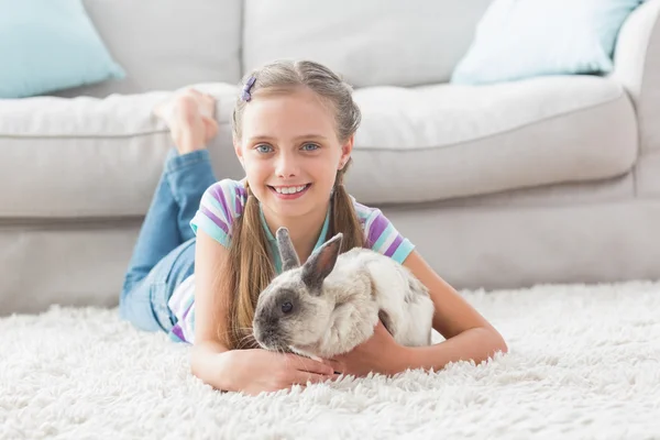 Girl with rabbit lying on rug in room