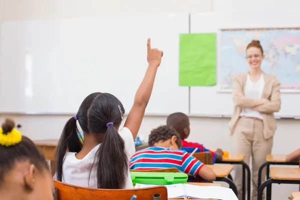 Pupils raising hand during geography lesson in classroom