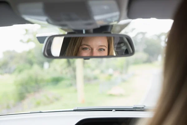 Young woman in the drivers seat looking in the mirror