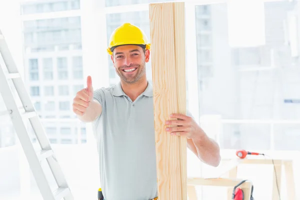 Carpenter holding plank in building