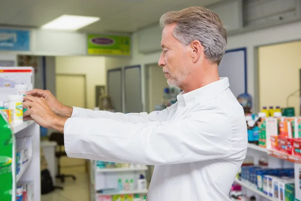 Pharmacist taking medicine from shelf