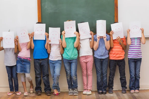 Cute pupils with funny faces in classroom