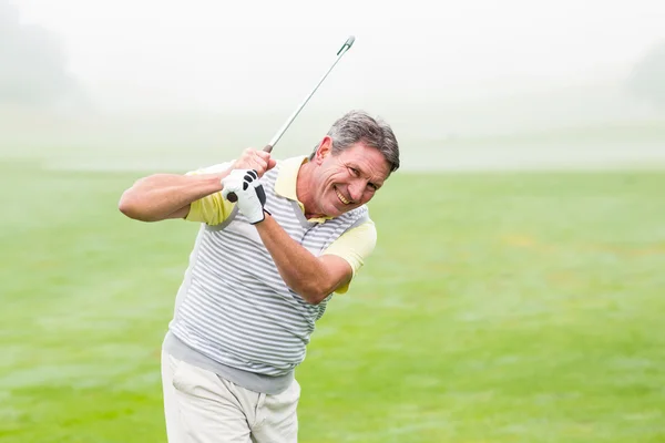 Golfer swinging his club on course