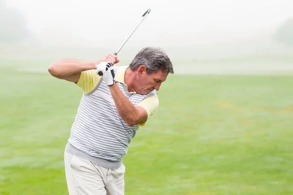 Golfer swinging his club on course