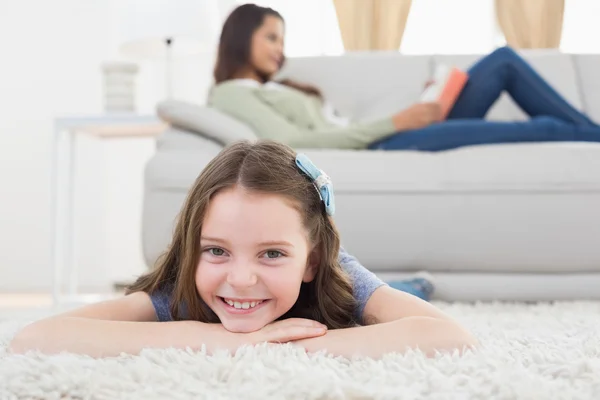 Girl lying on rug while mother relaxing