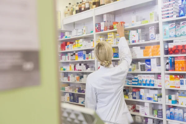 Rear view of student taking medicine from shelf