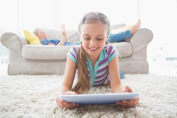 Girl using digital tablet on rug