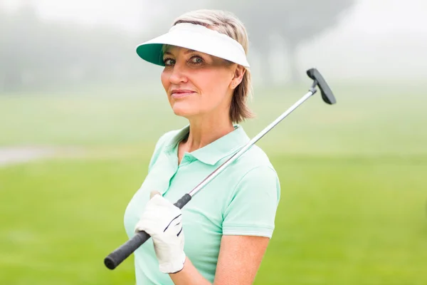 Golfer standing and swinging her club