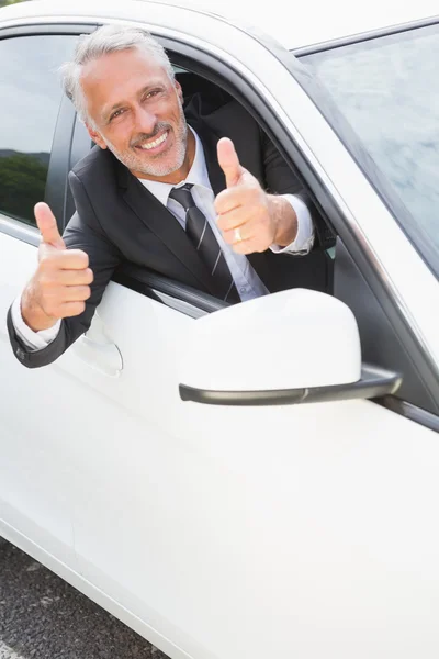 Businessman smiling at camera showing thumbs up