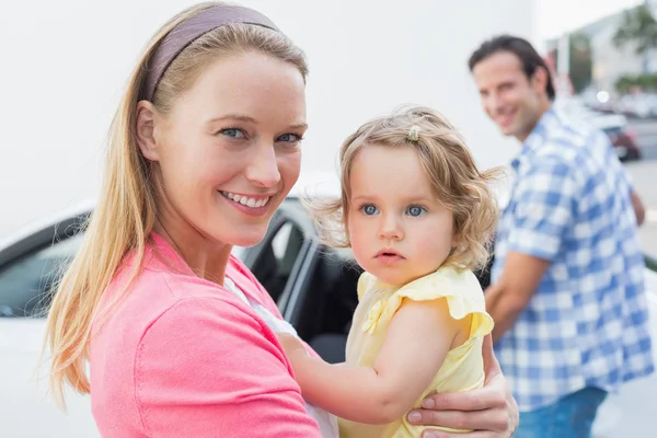 Parents carrying baby and her car seat