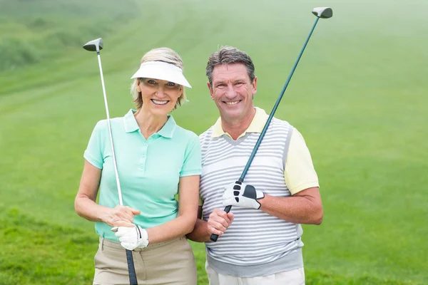 Golfing couple smiling holding clubs