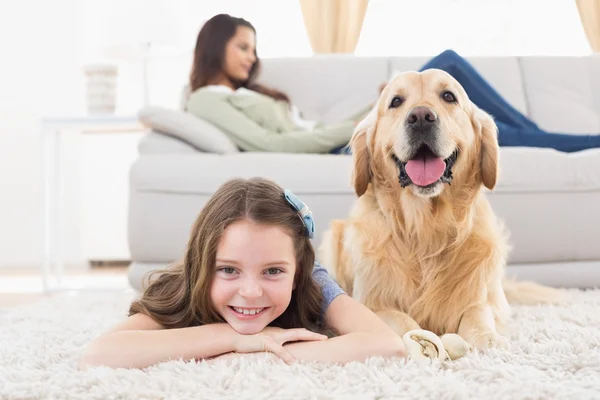 Girl with dog lying on rug at home