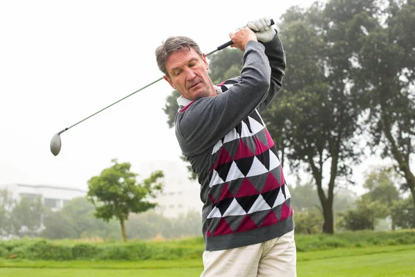 Golfer swinging his club on the course