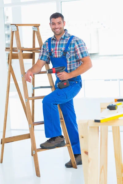 Carpenter with power drill climbing ladder