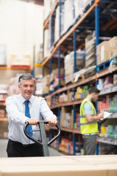 Manager pulling trolley with boxes in front of his employee