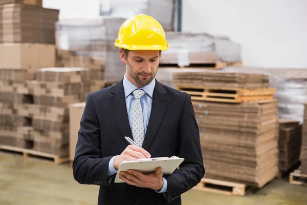 Warehouse manager writing on clipboard