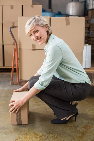 Warehouse manager picking up cardboard box