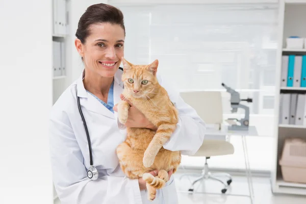 Smiling veterinarian with cat in her arms