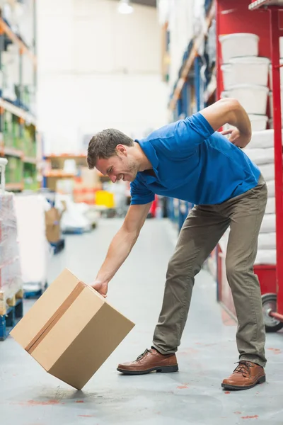 Worker with backache while lifting box in warehouse