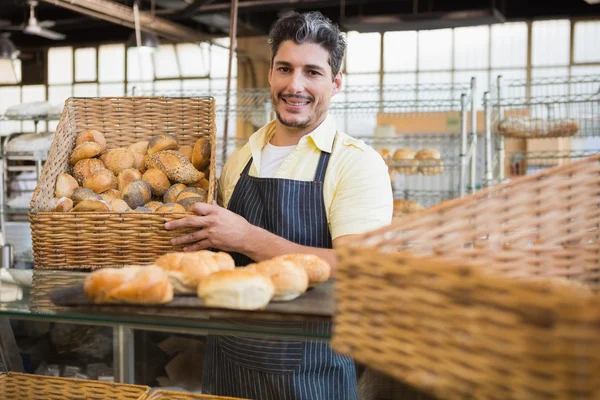 Happy worker holding basket of bread