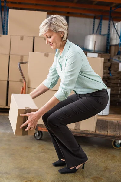 Warehouse manager picking up cardboard box