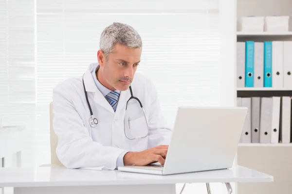 Serious doctor using laptop