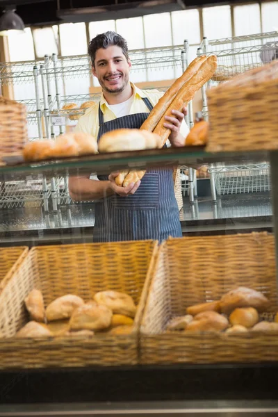 Smiling waiter holding two baguettes