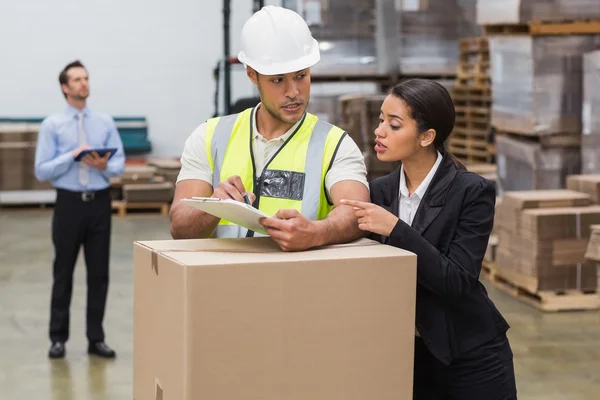 Warehouse manager and worker looking at clipboard