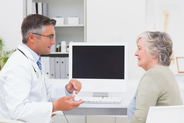 Male doctor conversing with senior patient