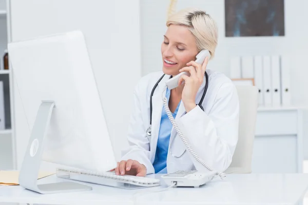 Doctor on call while using computer in clinic