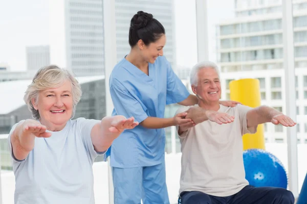 Trainer assisting senior couple in exercising