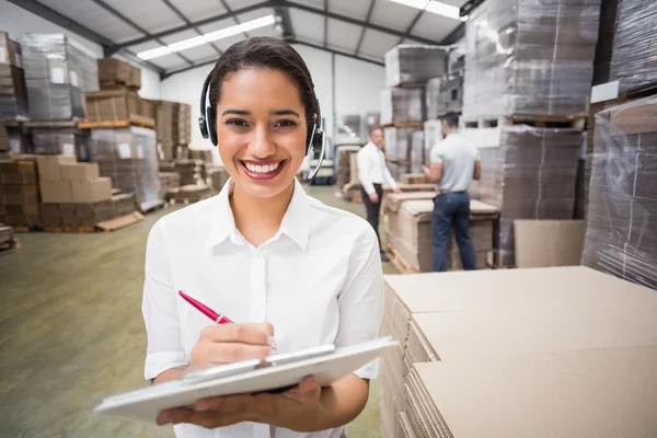 Warehouse manager writing on clipboard