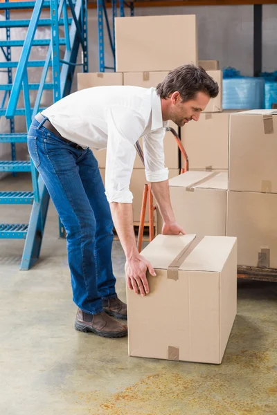 Warehouse manager picking up cardboard box