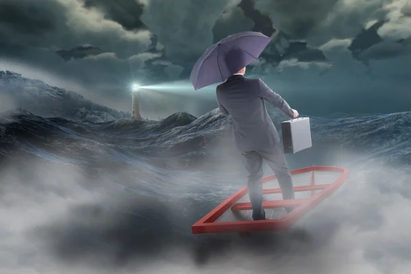 Businessman in boat with umbrella