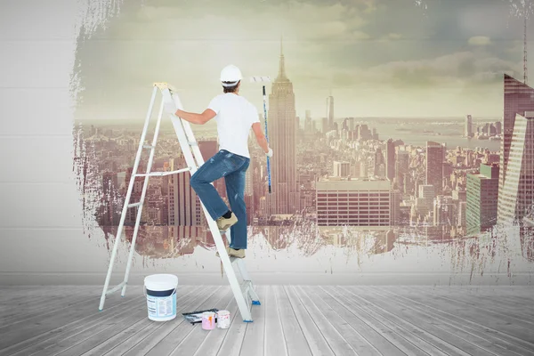 Man on ladder painting with roller