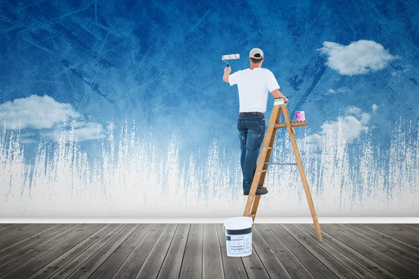 Man on ladder painting with roller