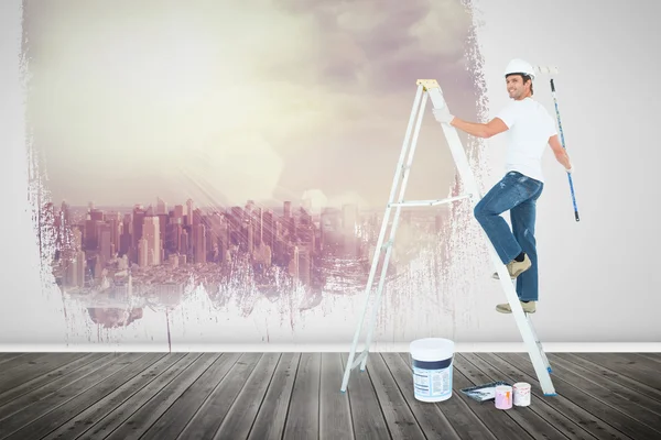Happy man on ladder painting with roller
