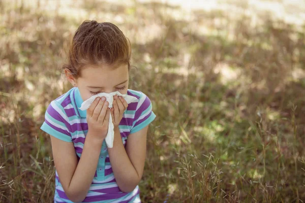 Cute little girl blowing her nose in park